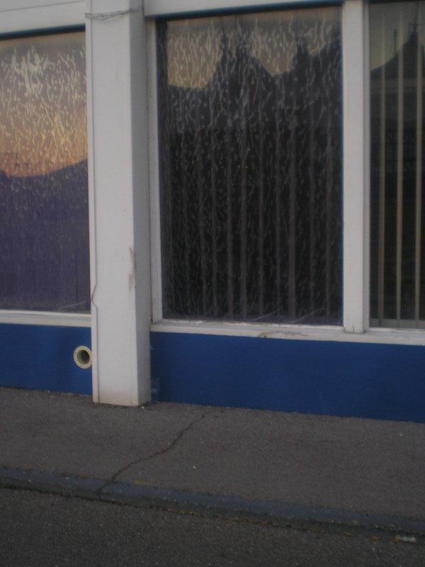 A downstairs window at the back of the old building with the Skyline reflected